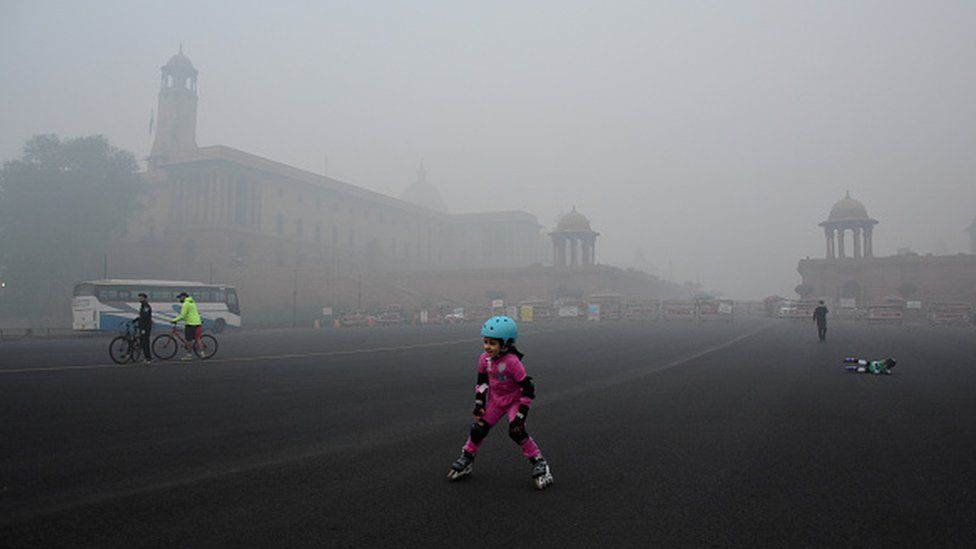 Дети катаются на коньках в густом смоге возле дома президента в Нью-Дели