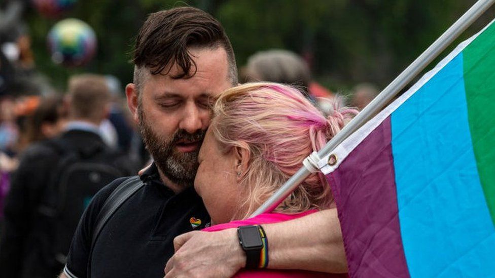 Image shows two protesters embracing