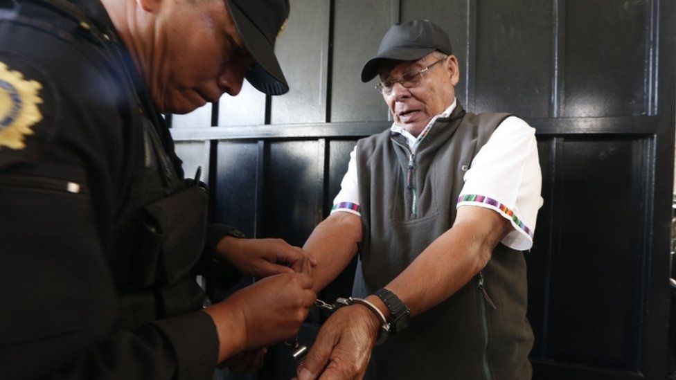 A police officer removes handcuffs from Benedicto Lucas Garcia, a former army commander credited with founding Guatemala's paramilitary groups, before escorting Lucas Garcia into a courtroom in Guatemala City, Wednesday, Jan. 6, 2016.