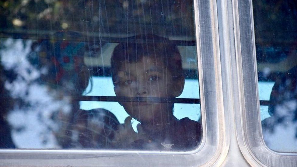 A child looks through the window of a bus carrying migrants near McAllen Detention Facility, McAllen, Texas