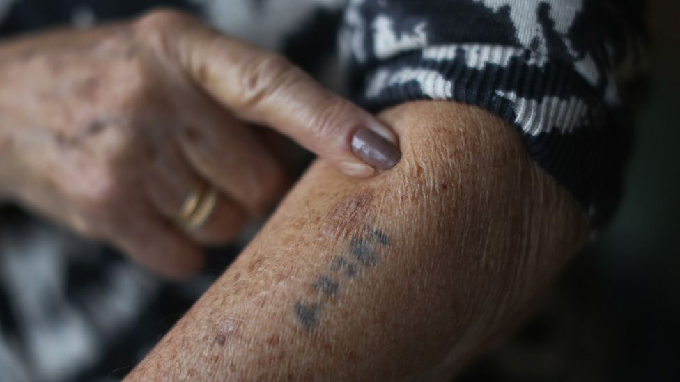 Finger points to Auschwitz tattoo on arm
