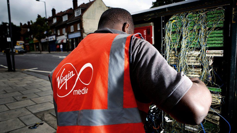 A Virgin Media technician works on the cabling in a roadside cabinet