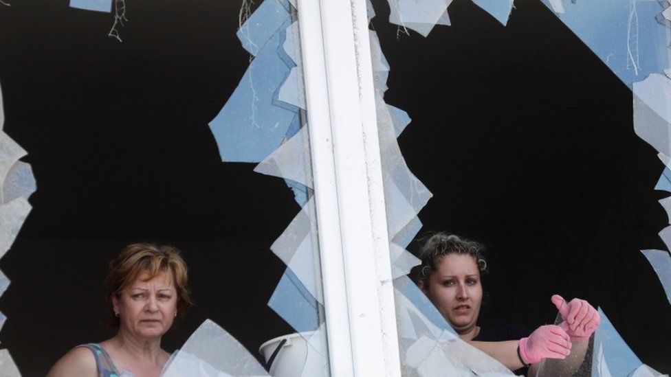 Women look through damaged windows of a building in the aftermath of a rare tornado that struck and destroyed parts of some towns, in Moravska Nova Ves village