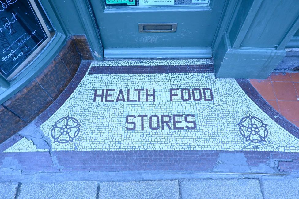 A mosaic in the entrance to a doorway on Gillygate that says 'Health Food Stores'