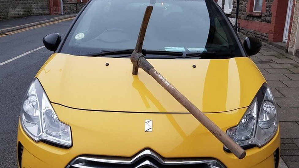 Damaged car with pickaxe in its bonnet