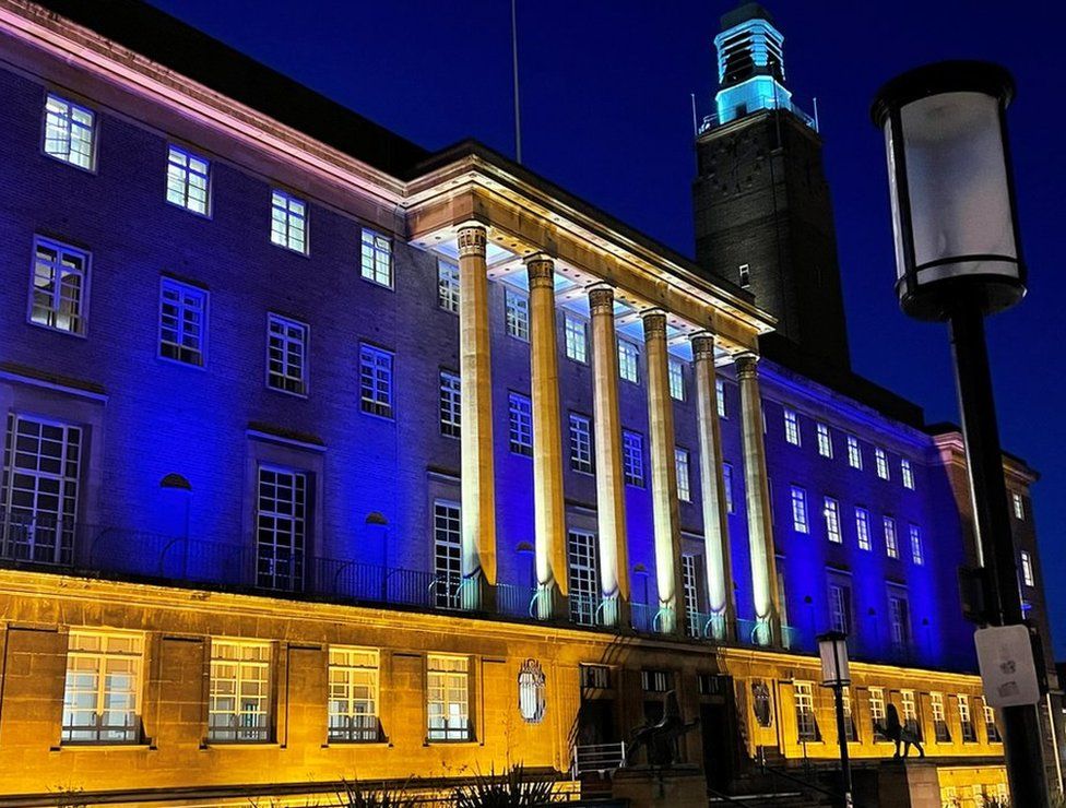 Norwich City Hall illuminated by yellow and blue lights in solidarity with the Ukrainian people