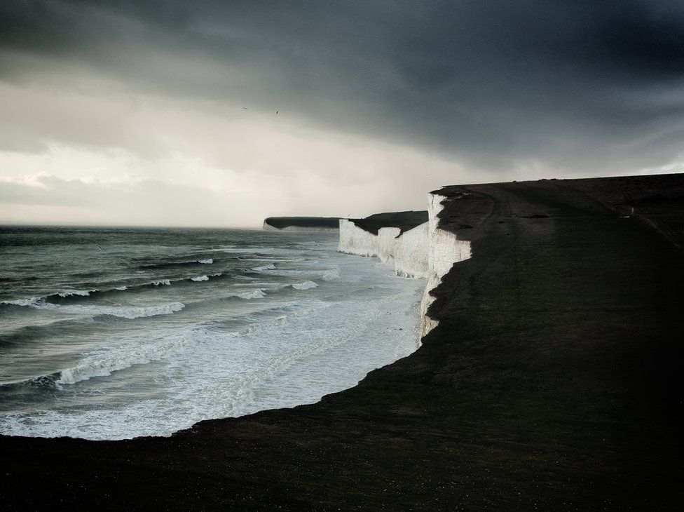 A view of white cliffs with a dark and rough sea beneath