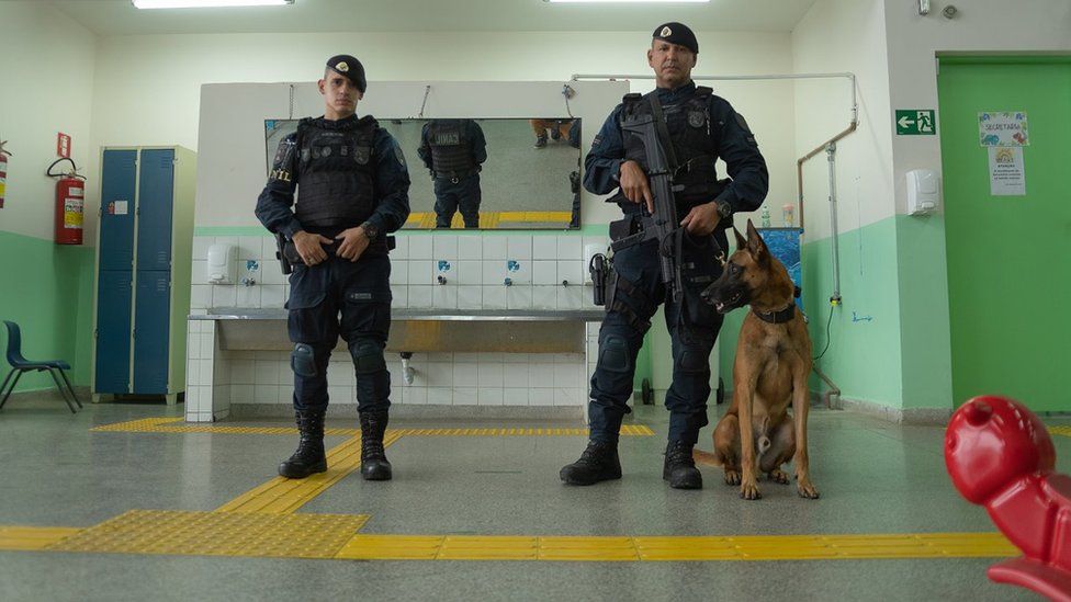 Two policemen and a dog patrol a kindergarden in Suzano, a city in São Paulo that suffered a tragic school shooting in 2019