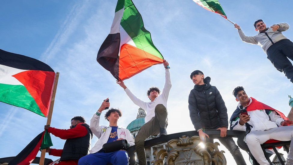 Boys waving flags on gates of City Hall