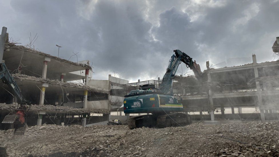 An excavator pulls down concrete levels