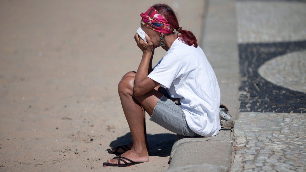 A woman covering her face sat on the pavement in Rio de Janeiro.