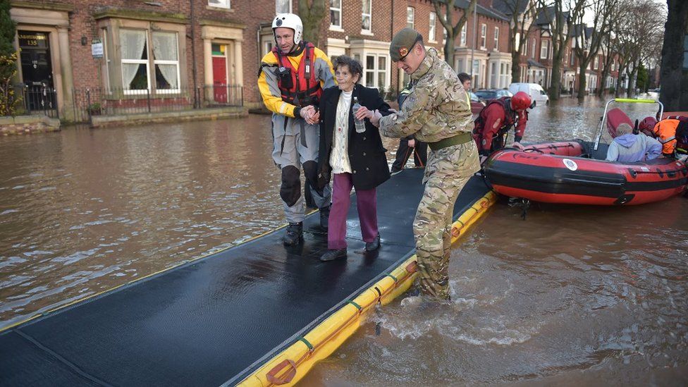 A woman is helped along an inflatabale walkway in Carlisle