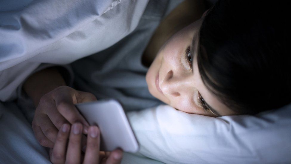Woman using her smartphone in bed