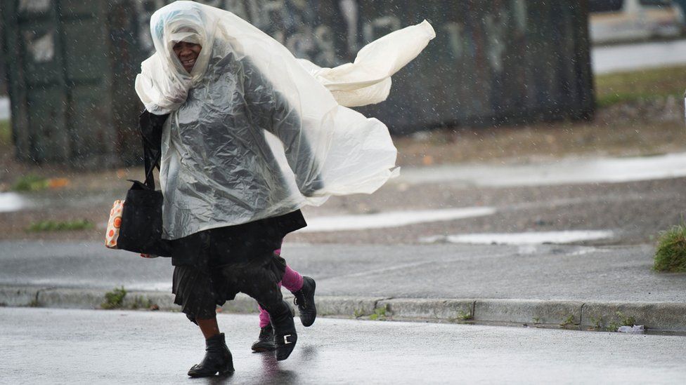 A woman and a child run across the road, in makeshift raincoats in an informal settlement, in Langa, during one of the most intense storms that has hit the Western Cape Province in more than a decade, on June 07, 2016, in Cape Town