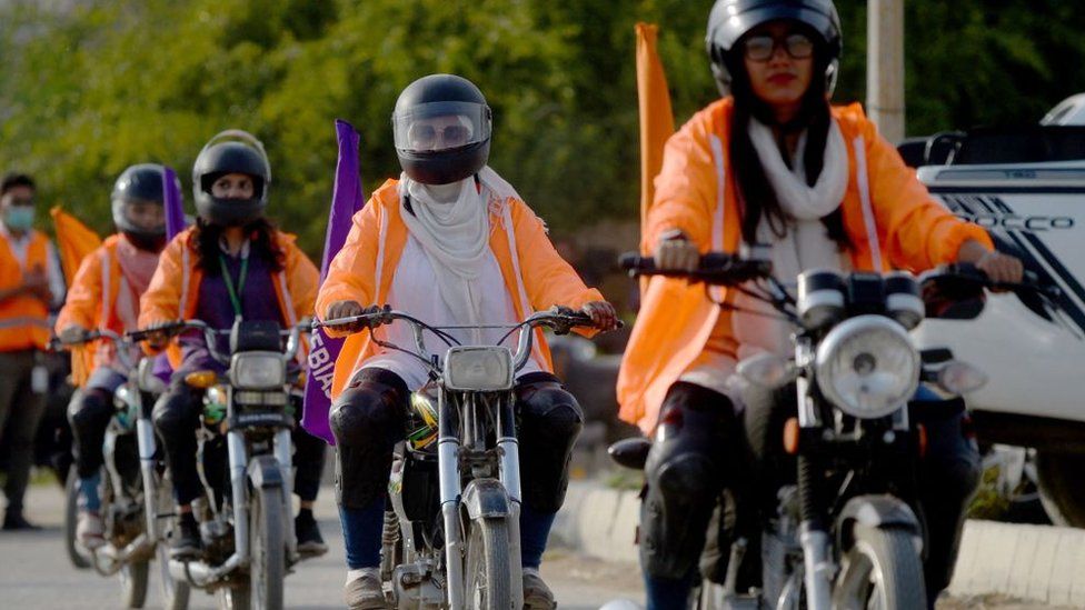 Женщины в Пакистане ездят на мотоциклах, носят шлемы и оранжевые куртки.