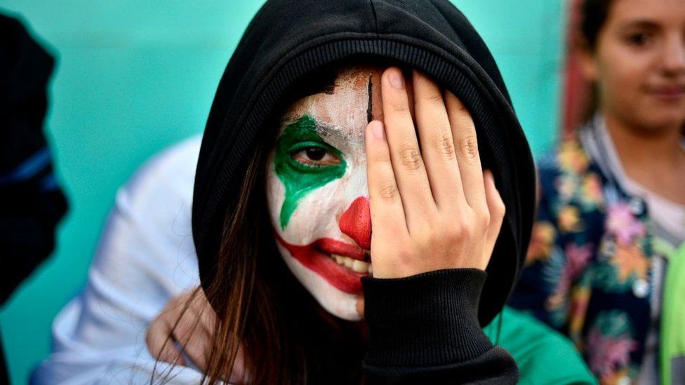 A protester wearing face paint in the colours of the national flag