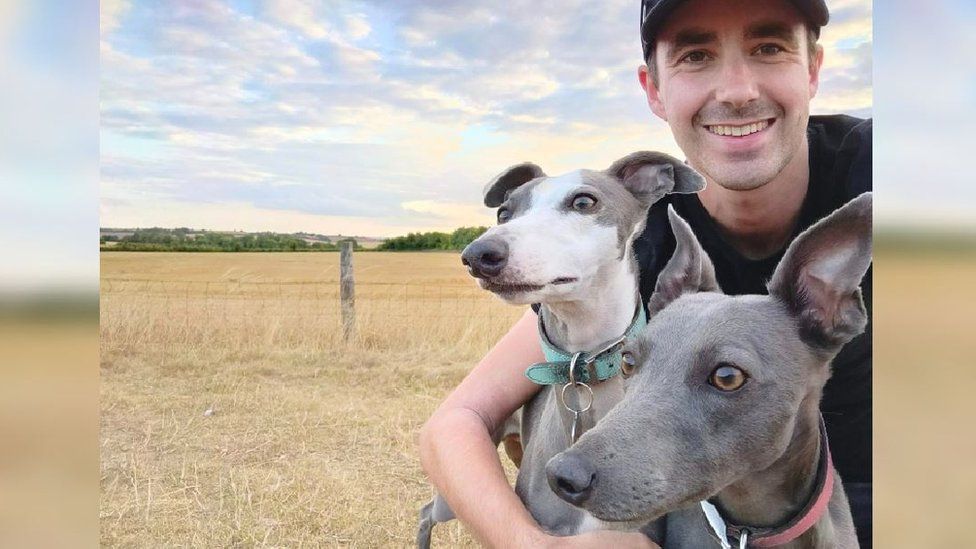 Shaun Reynolds with his two dogs in front of a field