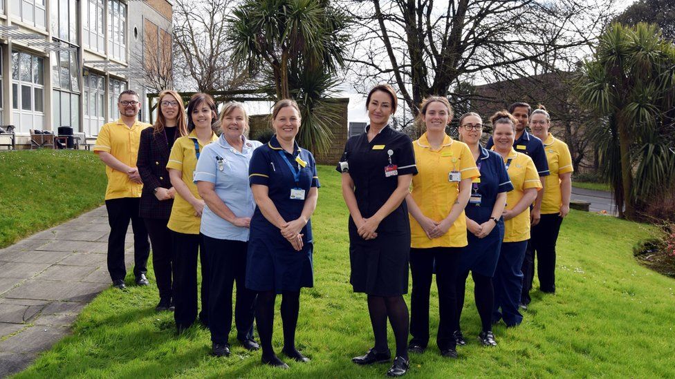 Somerset NHS Foundation Trust's specialist dementia and delirium team - 10 nurses wearing yellow and blue are standing outside smiling into the camera