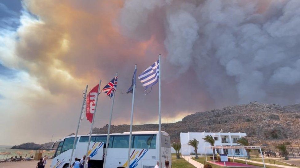 Smoke rises from wildfires adjacent   a beach