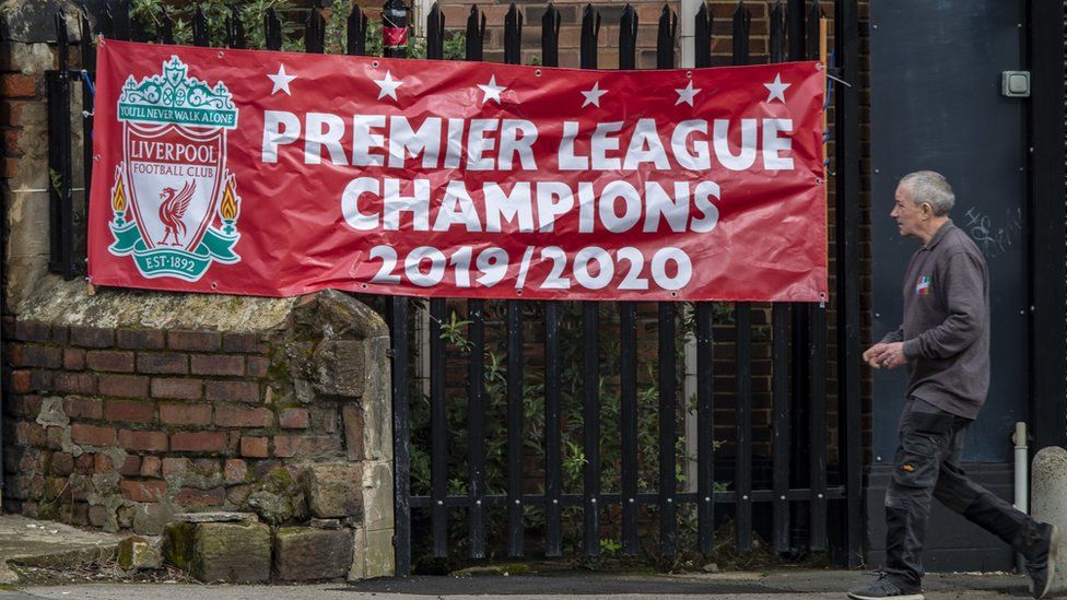 Man walks past a banner saying Liverpool Premier League Champions 2019-20