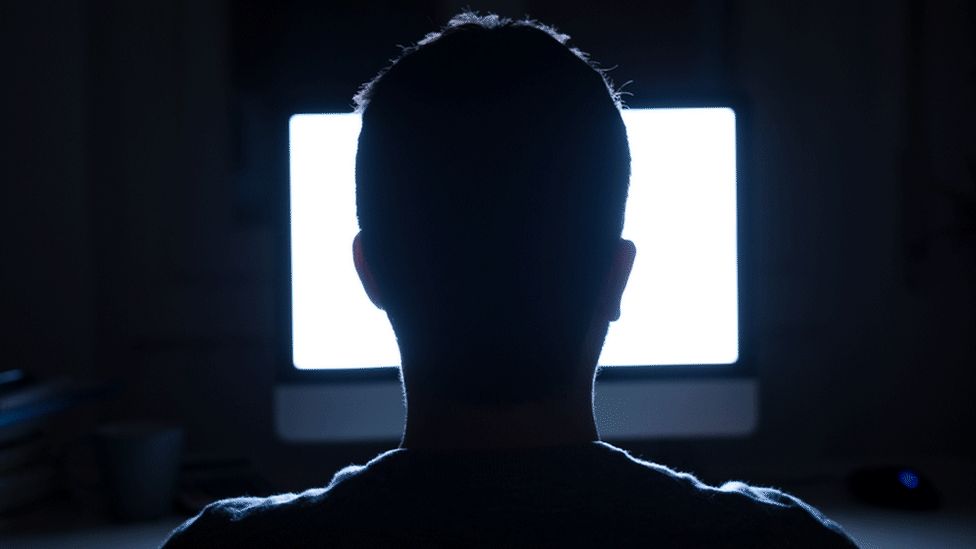Silhouette of man on computer