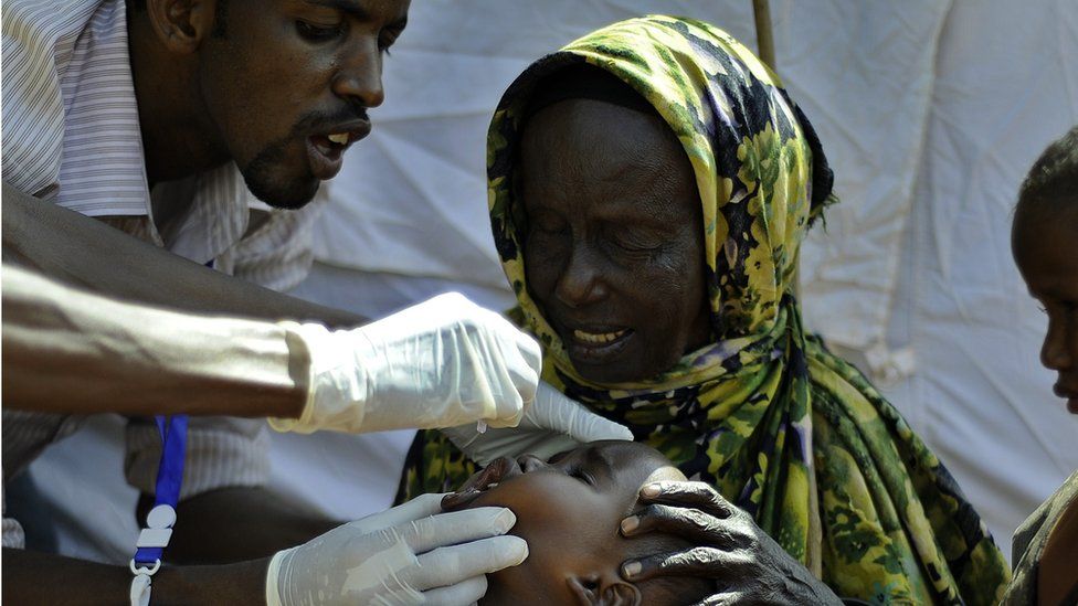 Howa Hassan (C), a blind Somali octogenarian refugee sits with her grandchildren as one of them is vaccinated at a paediatric vaccination centre at Hagadere refugee site within the Dadaab refugee complex in Kenya's north-east province on August 1, 2011