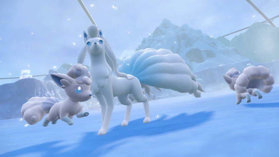 Three Pokémon frolic in a snowy, mountainous landscape. Two smaller, fox-like creatures are prancing around a larger animal that looks like a canine with a large, peacock style fanned tail. All three are pure white but with bright blue eyes and blue markings on their ears.