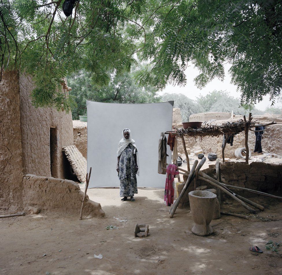 A woman stands in her village.