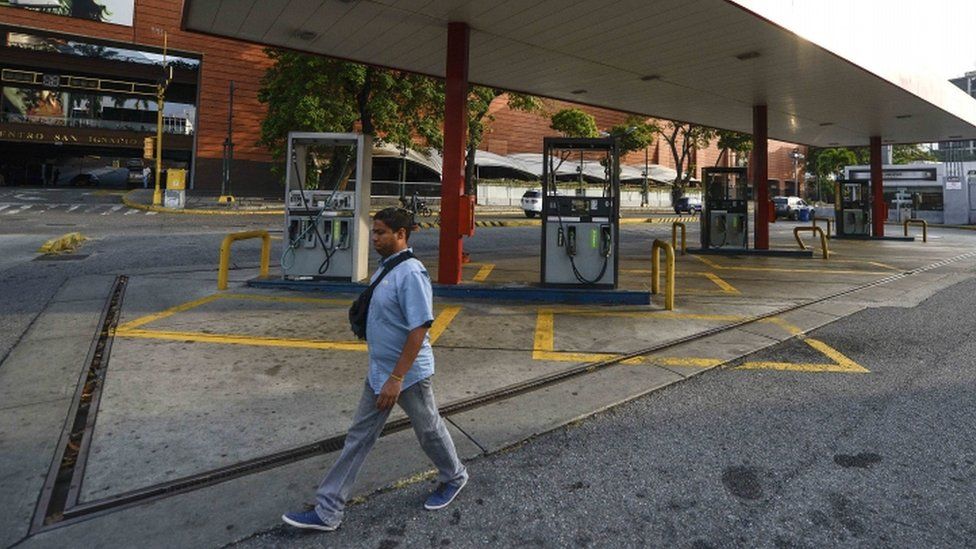 Un hombre caminando por una gasolinera abandonada.