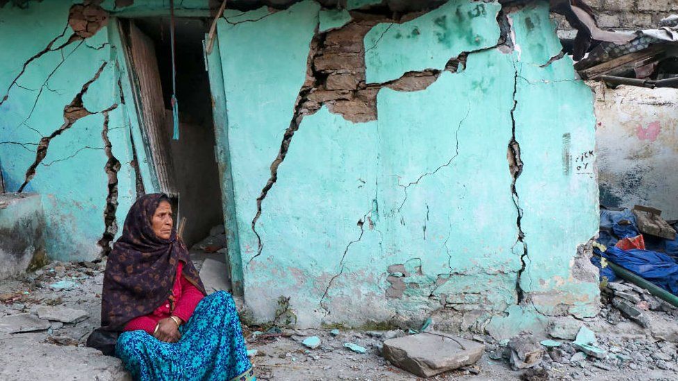 A woman sits beside a cracked wall of her house at Joshimath in Chamoli district of India's Uttarakhand state on January 10, 2023.