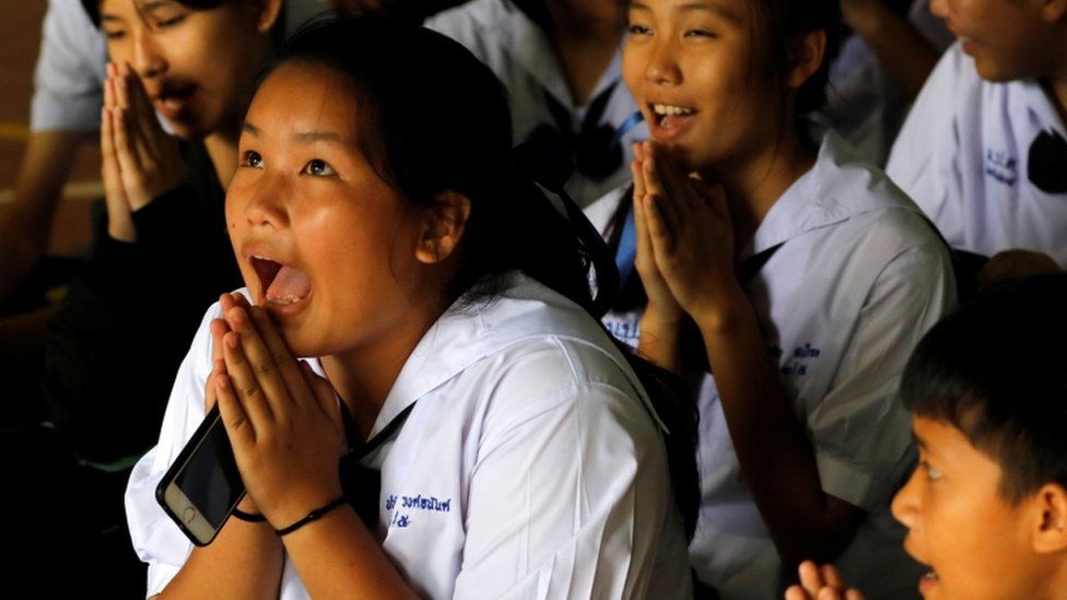A girl celebrates after hearing some of her classmates had been potentially released from cave where they were trapped