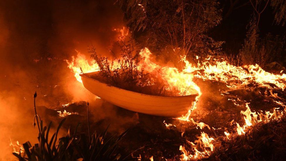 A boat in a backyard catches alight in a bushfire in Hillside in New South Wales