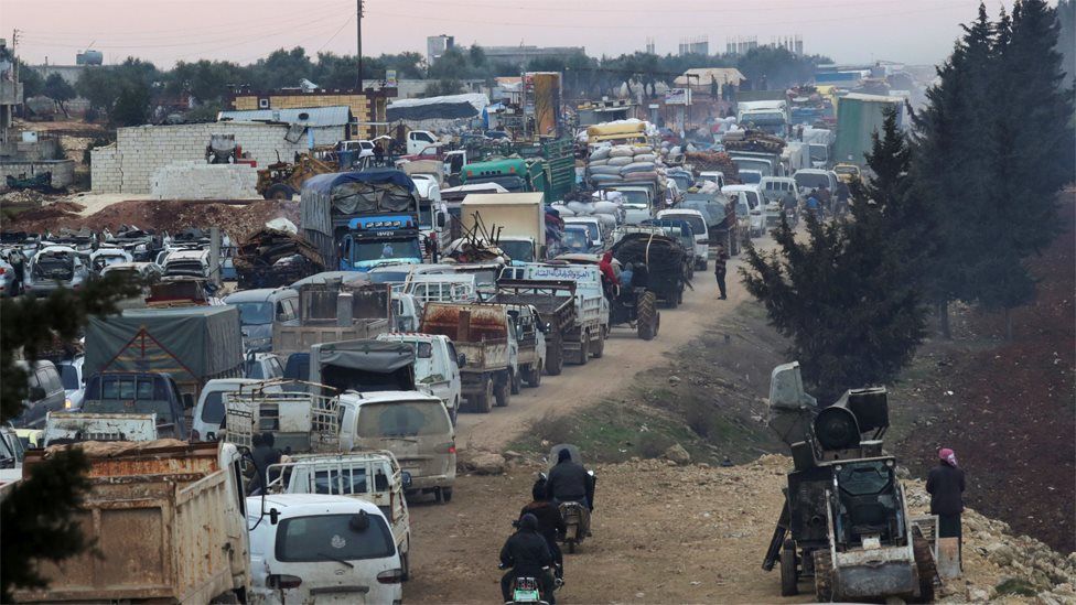 Displaced Syrians travelling in vehicles queue to pass through the town of Sarmada in Idlib province (28 January 2020)