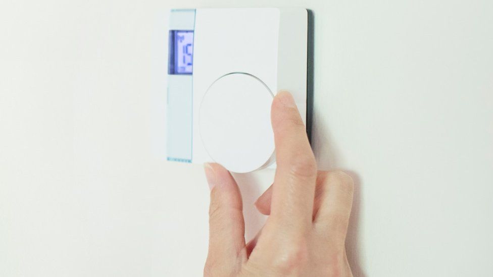 Hand turning up heating thermostat