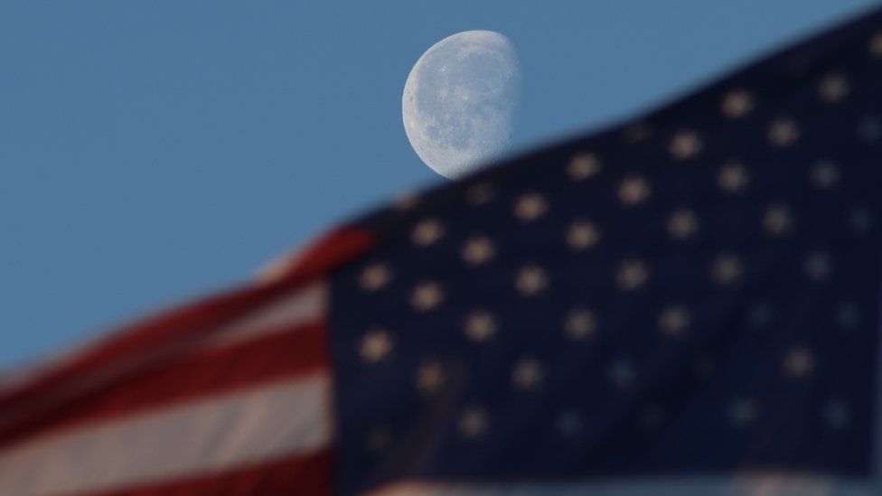 The Bulging Moon rises over the sky at the early morning hours as a flag of the United States waving, in New Jersey, United States on March 30, 2024.