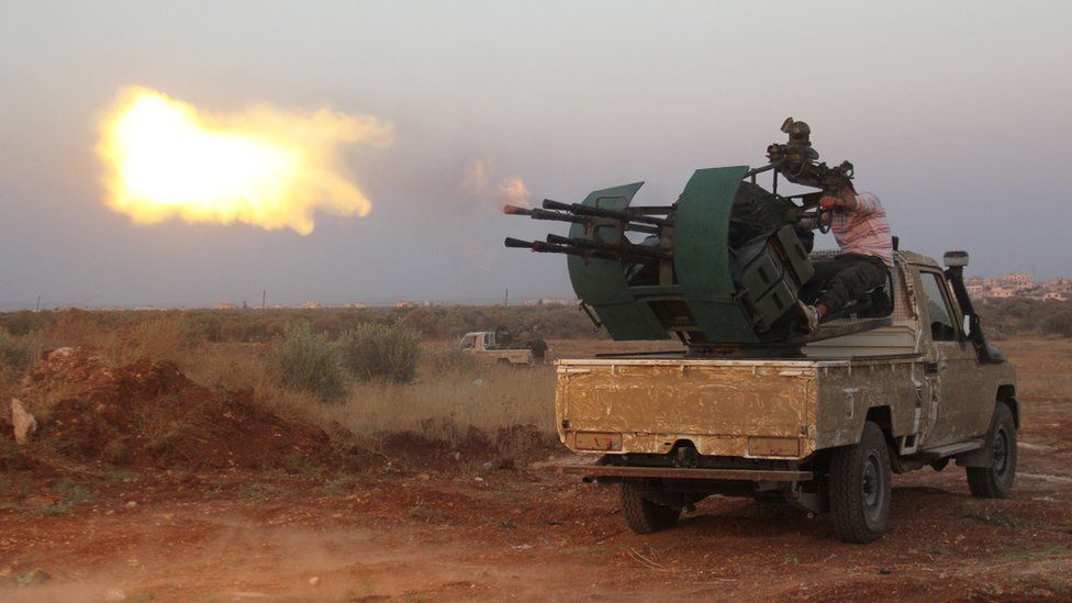 Rebel fighters fire a heavy machine gun during clashes with Syrian pro-government forces