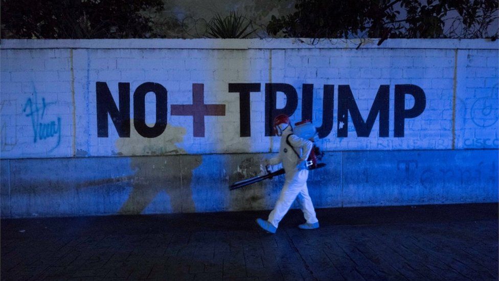 A man walks past graffiti reading No more Trump