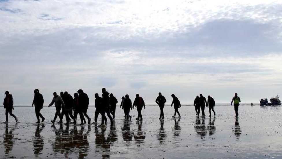 A group of migrants walking on a beach