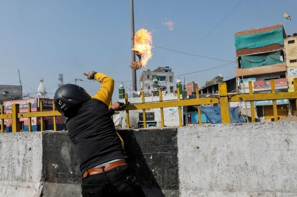 A man supporting a new citizenship law throws a petrol bomb at a Muslim shrine during a clash with those opposing the law in New Delhi India, February 24, 2020