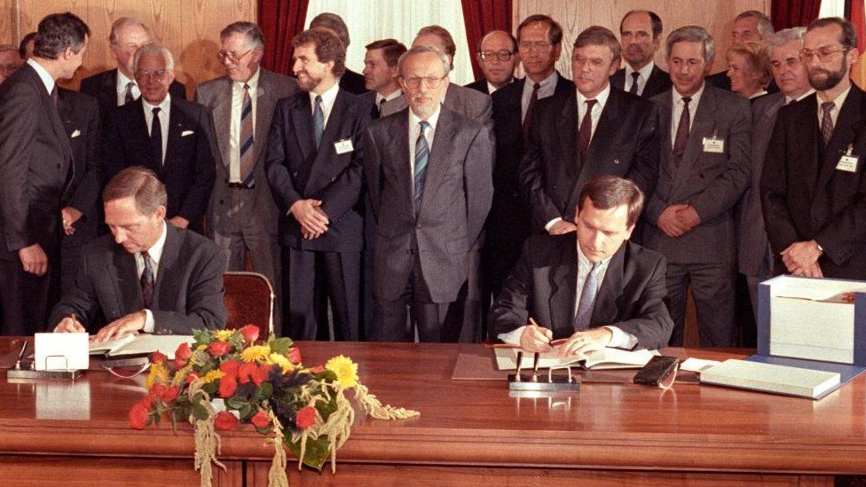 West German Interior Minister Wolfgang Schaeuble (L) and East German State Secretary Guenter Krause (R) sign the contract on German reunification as East German Prime Minister Lother de Maiziere (C) looks on, August 31, 1990