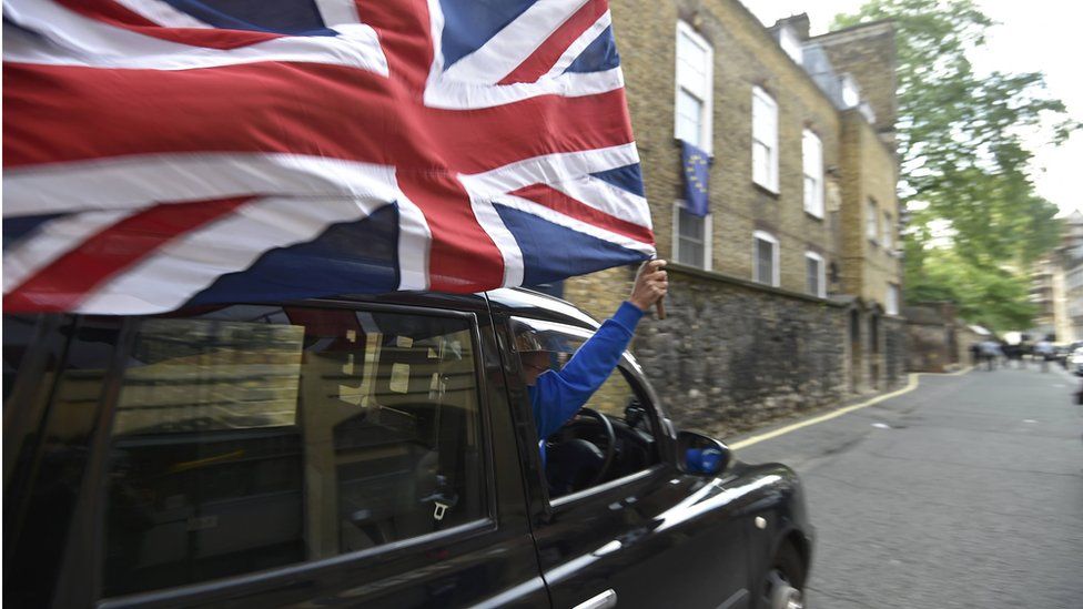 A London taxi driver waves a union jack flag from his cab.