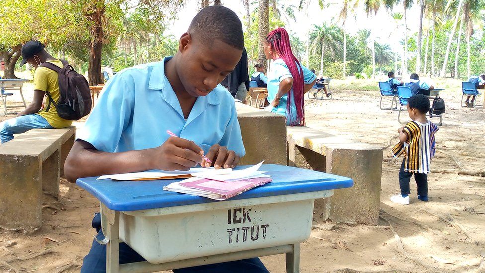 Pupil writing at a desk outside
