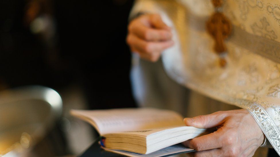 A photo of a priest holding a book