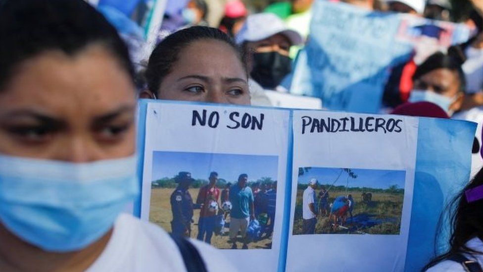 A woman holds a sign that reads "They are not gang members" and features photos of her relatives who were detained during a state of emergency, in San Salvador, El Salvador July 19, 2022.