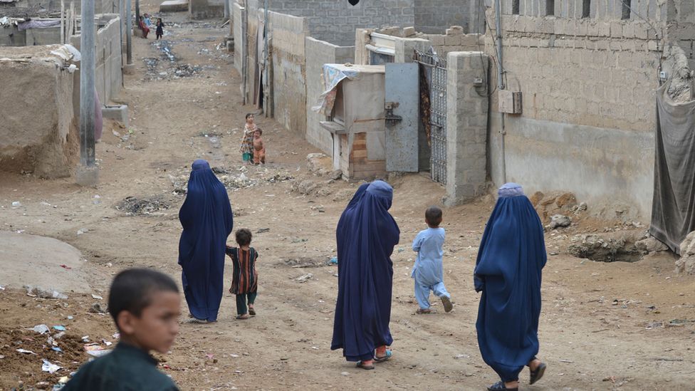 Afghan women walk through an Afghan refugee camp in Karachi