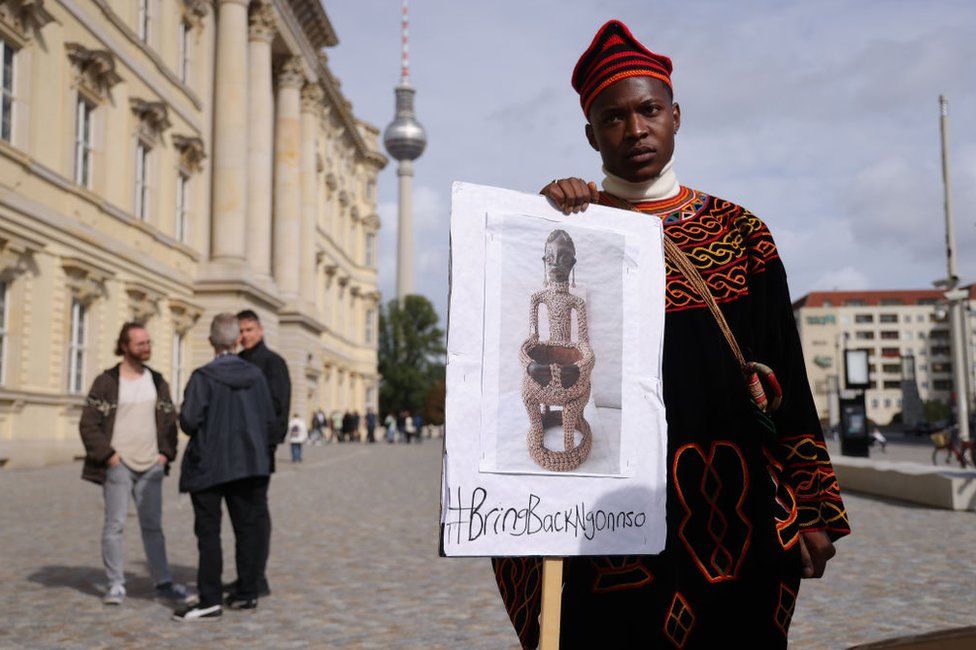 A protester from Cameroon seeking the return of the Ngonnso statue stands outside the Humboldt Forum during the opening of the Humboldt's Ethnological Museum and the Museum for Asian Art. A small group of protesters from Cameroon stood outside the Humboldt Forum to demand the return of the statue, which they say is a sacred, spiritual artefact of the Nso people and which they say was looted by Germany in 1902 while Cameroon was a German colony.