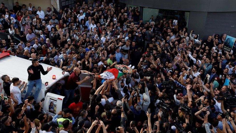 Palestinians carry the body of Al Jazeera journalist Shireen Abu Aqla in front of Al Jazera's offices in the occupied West Bank city of Ramallah (11 May 2022)