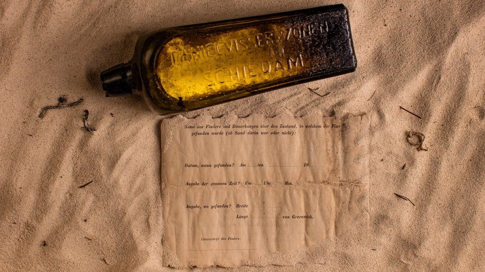 The bottle and the note placed on a sandy surface