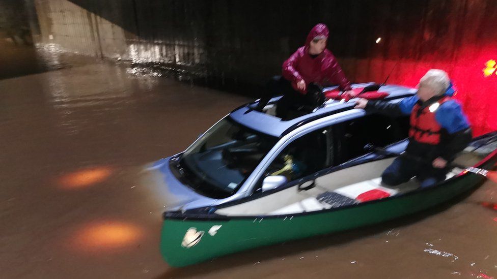 Woman being rescued from car in floodwater