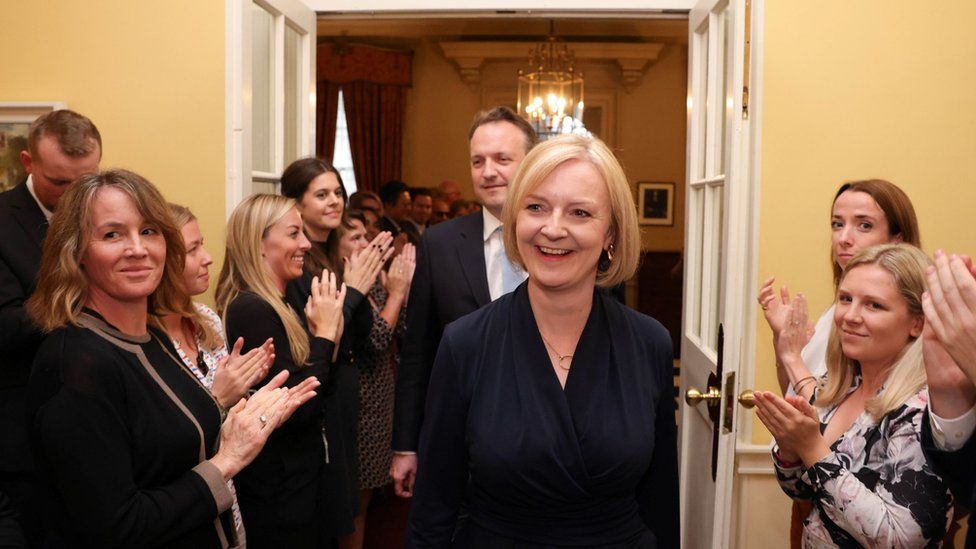 Liz Truss and her husband are applauded as they walk through the corridor of 10 Downing Street